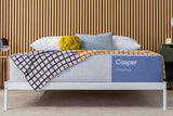 Casper Cloud One Mattress on a bed frame with pillows and a folded blanket