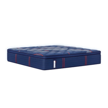 Full view of the Sealy Posturepedic® Elite Albany 15" Soft Euro Top Mattress in navy blue with a quilted top surface. The mattress features a plush pillowtop design with white diagonal striped patterns and button tufting across the sleep surface. Vertical red accent lines run along the sides of the mattress, highlighting its multi-layered construction. A Sealy brand tag is visible on the front side. The mattress is photographed at an angle against a white background, showcasing its substantial height